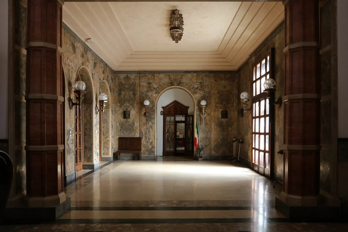 The marble atrium of the palace, with two tall red-brown columns, mottled stone walls and a coffered ceiling
